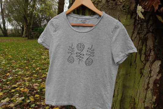 Front view of the light grey T-shirt outdoors, displaying the centred hand-stamped artwork