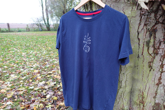 Full front view of the navy blue T-shirt outdoors, showing the centred hand-stamped artwork and red inner neck trim