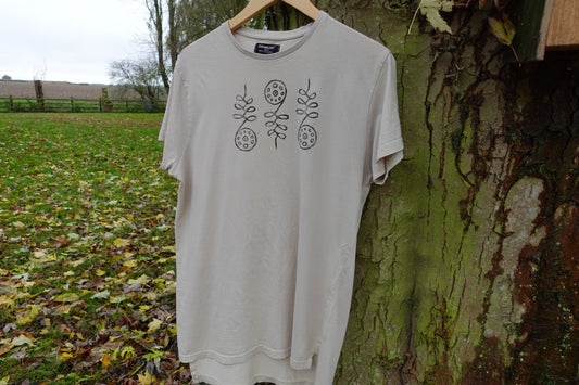 Full front view of the light beige T-shirt outdoors with the centred hand-stamped artwork.