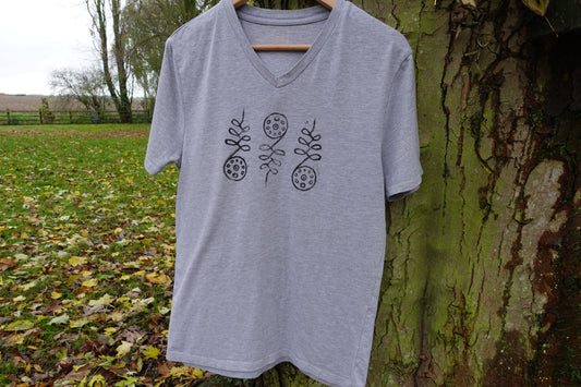 Full front view of the light grey V-neck T-shirt outdoors, showing the centred hand-stamped artwork