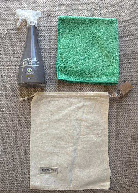 Green microfiber cloth, white drawstring bag, and gray bottle on a textured surface