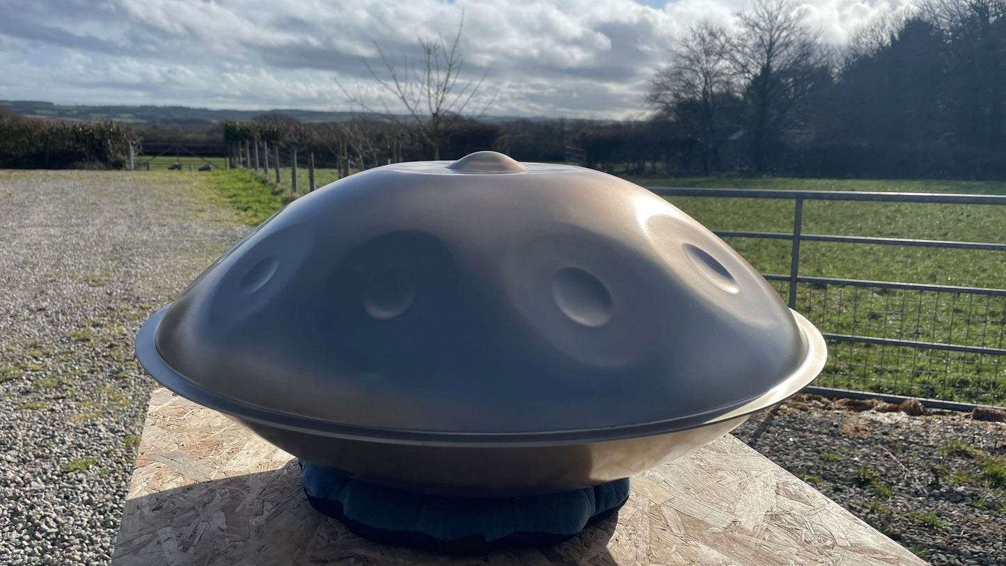 Handpan instrument on a stone surface with a rural landscape in the background