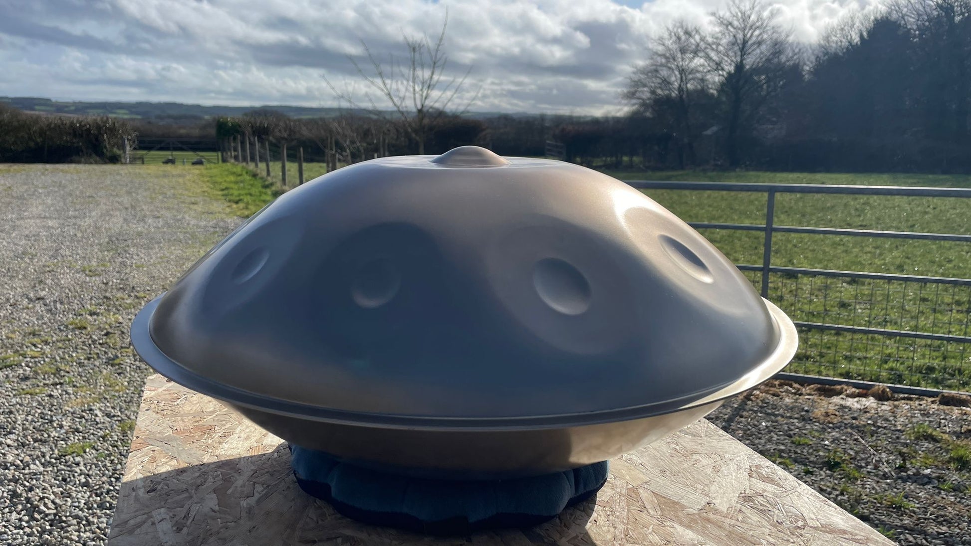 Handpan instrument on a stone surface with a rural landscape in the background