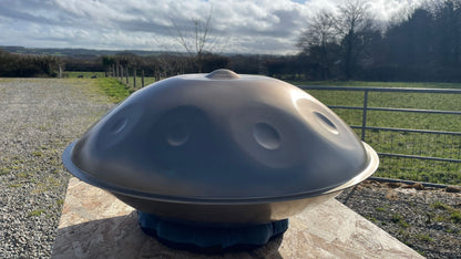 Handpan instrument on a stone surface with a rural landscape in the background