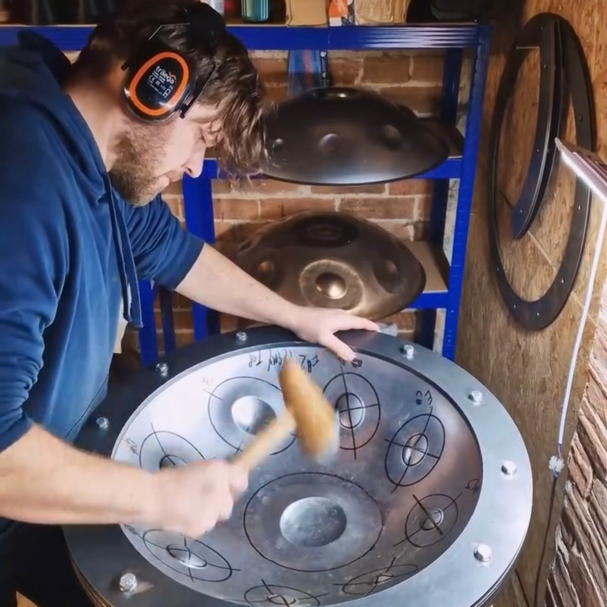Person shaping a handpan in a workshop setting