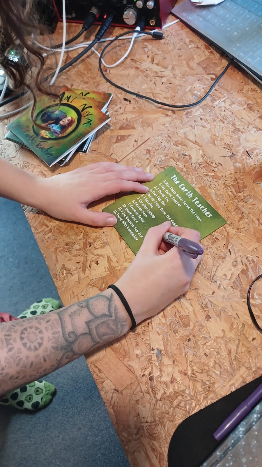 Person writing on a cd with a pen on a wooden surface