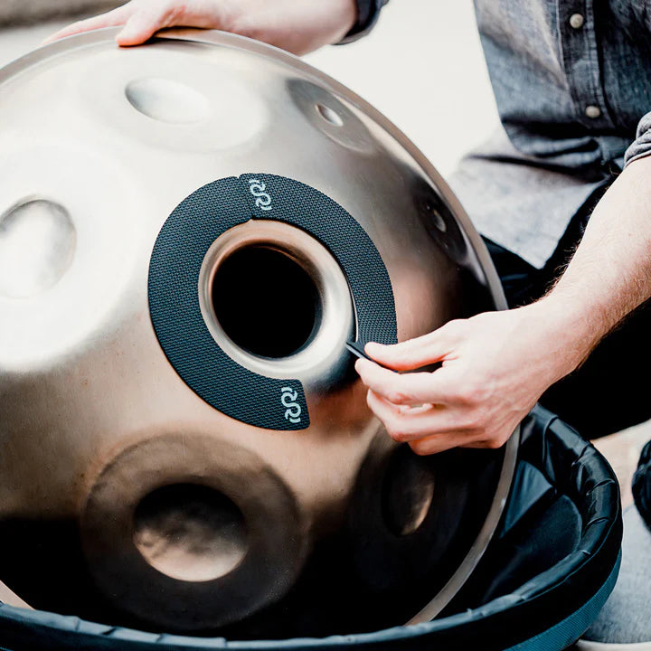 Handpan with Rhythm Rest magnetic grips attached around the gu while being adjusted by hand