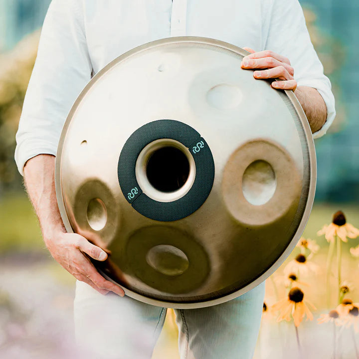 Person holding a handpan fitted with Rhythm Rest magnetic grips outdoors