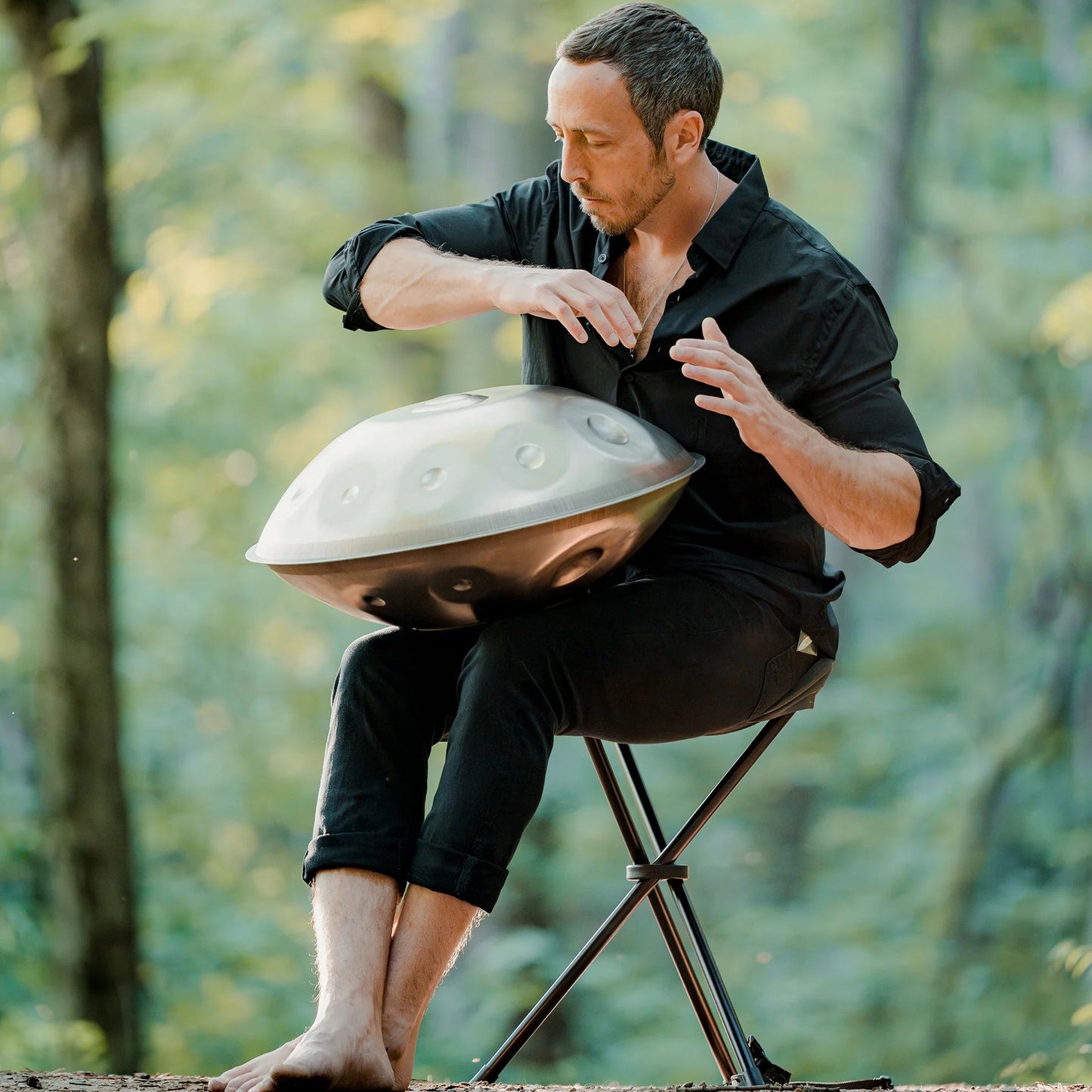 Person playing a handpan fitted with Rhythm Rest magnetic grips while seated outdoors